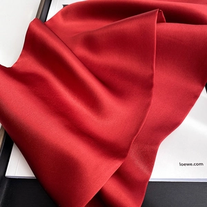 Macro shot of pure red silk scarf fabric with smooth satin finish and elegant luster