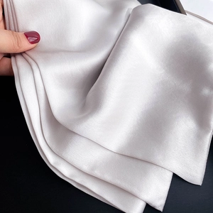 Close-up of lightweight champagne silk scarf with smooth satin finish and clean edges