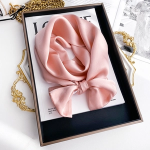 Detailed close-up of a pink silk neckerchief with satin gloss in a gold-rimmed tray