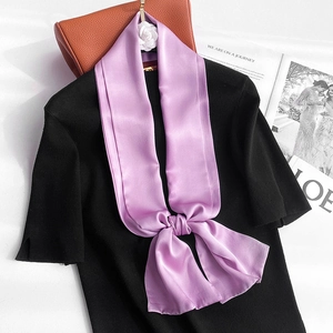 Detail of a lavender silk scarf tied in a bow with a white camellia on a black top