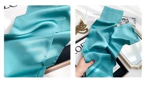 Detail view of lake green silk scarf with smooth texture and pearl-like glossy finish