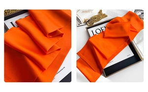 Detailed texture of vibrant orange silk scarf featuring smooth drape and satin finish