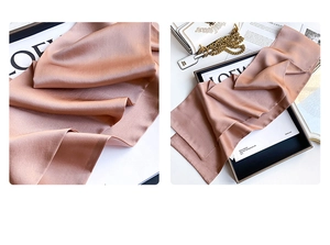 Detailed close-up showing the glossy silk texture and champagne gold sheen of the scarf