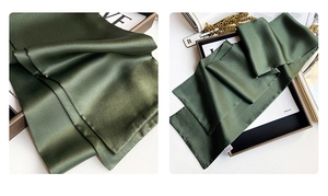 Detail of elegant dark green silk scarf with a smooth satin finish and premium texture
