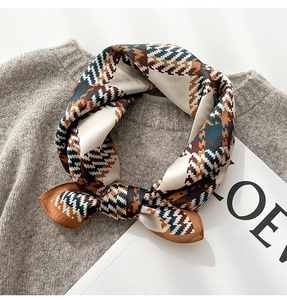 Detailed texture of silk scarf with houndstooth pattern on a grey knitted sweater