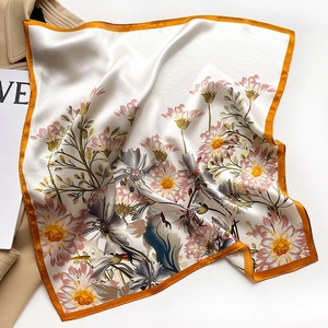 Detail view of floral silk square scarf with daisy prints on a trench coat background