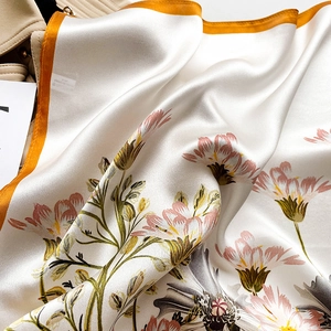 Detailed close-up of cream silk scarf featuring pink floral print and orange borders