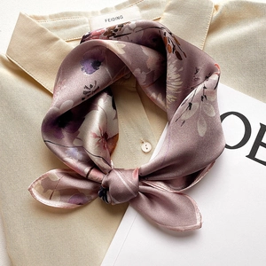 Elegant purple silk scarf with floral print tied on a beige shirt collar