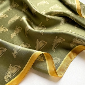 Detail of silk scarf showing olive green satin fabric with white harp patterns