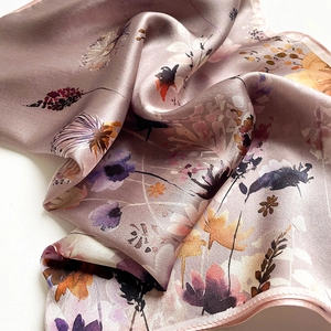 Detail of silk scarf with floral print and satin finish showing soft texture and rolled edges
