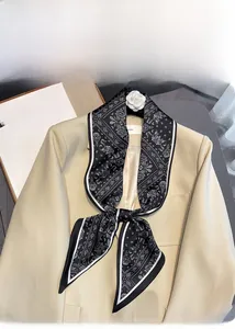 Close-up of black paisley pattern silk twilly scarf styled on a beige blazer collar