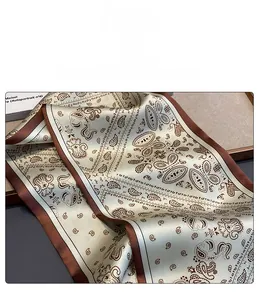 Detail of soft faux silk scarf featuring brown paisley patterns and smooth edges