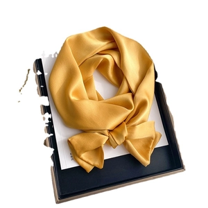 Elegant ginger yellow silk scarf tied in a bow and presented in a black gift box