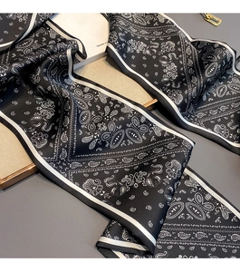 Close-up of black satin scarf with white paisley pattern and smooth silky texture