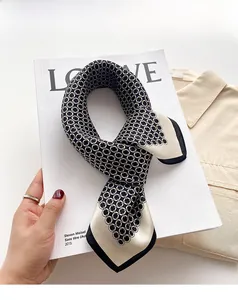 Détail d'un foulard en soie avec motif de chaîne géométrique en noir blanc et jaune