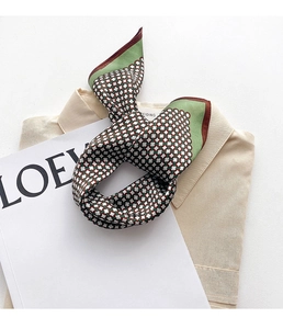 Détail d'un foulard en soie à motifs géométriques et bordure verte sur une chemise
