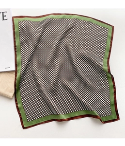 Détail d'un foulard en soie avec motif floral géométrique et bordure verte sur blanc