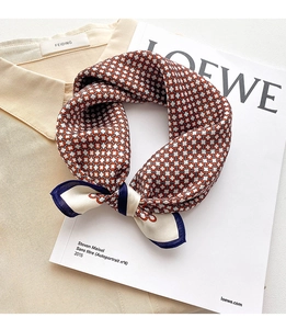 Gros plan d'un foulard en soie à motif de chaîne rouge bleu blanc sur chemise beige