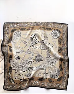 Macro detail of silk scarf showing champagne gold jewel and feather pattern prints