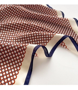 Gros plan du motif de chaîne géométrique sur le foulard en soie avec bordure bleue