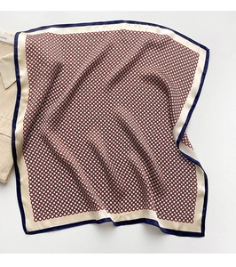 Détail de la texture géométrique en soie du foulard et du bord contrasté bleu marine