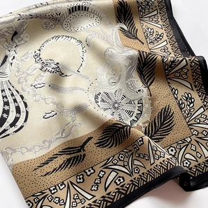 Detailed macro shot of vintage pattern silk scarf with elegant chain and feather motifs