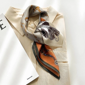 Close-up of silk square scarf with equestrian chain print tied on a shirt collar