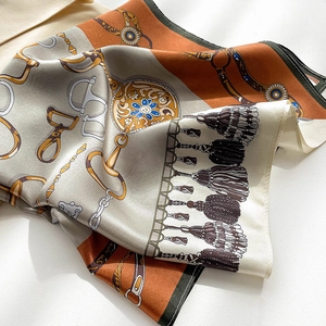 Detail of luxury silk scarf with equestrian chain prints and vibrant orange horsebit patterns