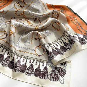 Detail of luxury silk scarf featuring equestrian chain prints and satin texture finish