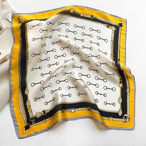 Detail of silk square scarf featuring equestrian chain print and smooth satin texture