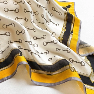 Close-up of silk scarf with classic horsebit and chain patterns in yellow and white