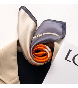 Detail of silk scarf with equestrian pattern draped over a beige suit jacket