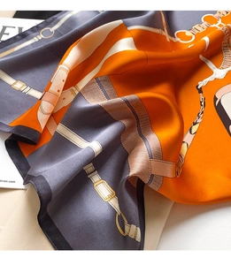 Detail of silk scarf with equestrian horse buckle patterns in orange and charcoal grey