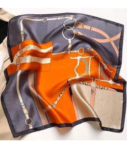 Detail of silk scarf with equestrian horse bit pattern next to a beige blazer