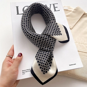 Foulard en soie avec motif de chaîne géométrique et bordure noire sur un magazine blanc