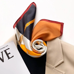 Silk square scarf with equestrian strap print and red hem over beige blazer