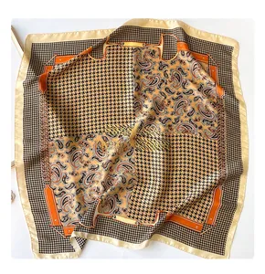 Close-up of houndstooth and orange paisley patterns on silk-like square scarf