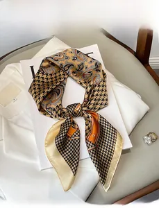 Detailed view of yellow and black houndstooth paisley silk scarf with pearl accessory