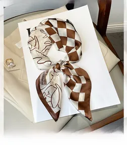 Close-up of silk-like scarf with checkerboard and line art patterns on a beige blazer
