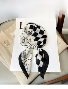 Detailed close-up of a black and white checkerboard silk scarf with abstract portrait lines