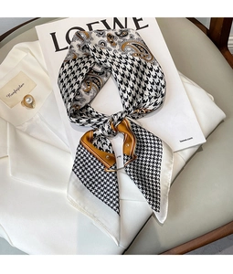 Close-up of houndstooth and paisley silk scarf styled on a white luxury blazer