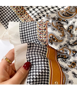 Detailed macro shot showing houndstooth patterns and golden chain motifs on silk scarf