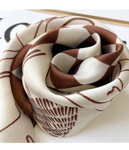 Macro view of soft silk-textured scarf featuring a brown geometric checkered spiral pattern