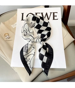 Detail of a silk-textured scarf featuring a checkerboard and abstract portrait design