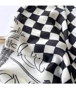 Detail of silk scarf with black and white checkerboard pattern and abstract face illustration