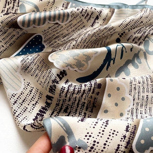 Gros plan d'un foulard en soie champagne avec motifs abstraits et texture douce et lisse