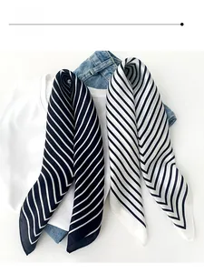 Close-up of diagonal striped silk scarves in black, white and navy on a casual outfit
