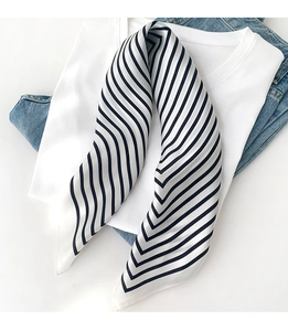 Detail of a chic black and white striped silk scarf folded on a white t-shirt and denim