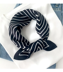 Close-up of black and white striped silk scarf styled as a knot on a casual outfit