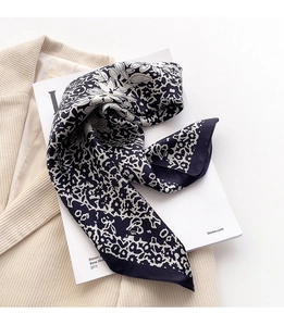 Dettaglio di un foulard in seta floreale abbinato a un blazer beige e rivista